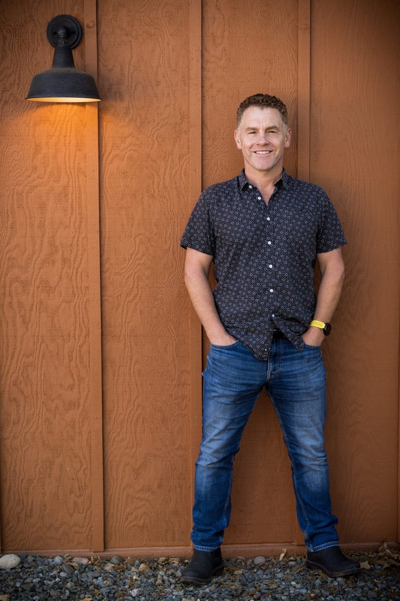 Jeromy Zajonc standing in front of a barn-style door, hands in pockets